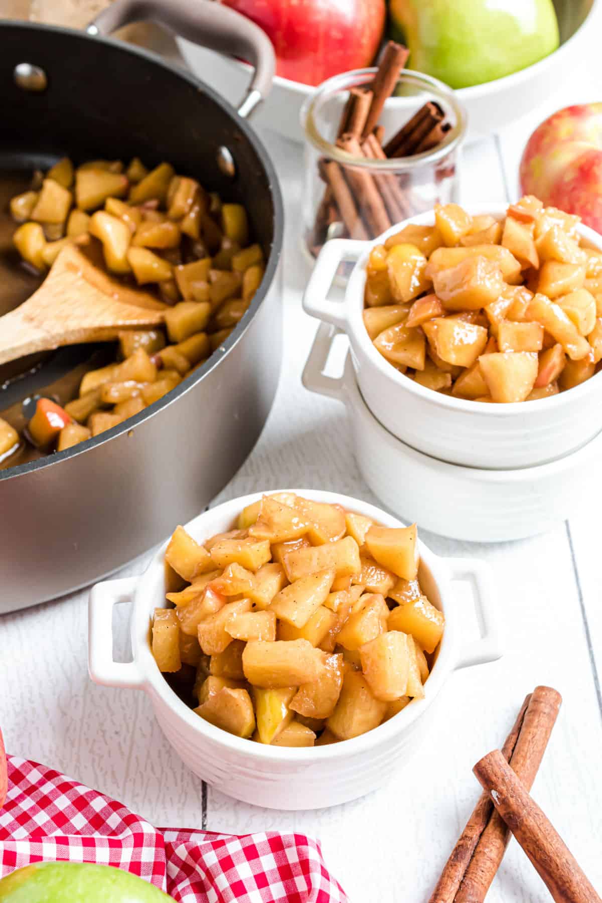 Fried apples served in a small white bowl with skillet in background.