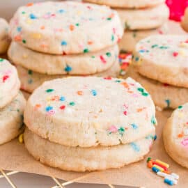 Stacks of sprinkle icebox cookies on parchment paper covered wire rack.