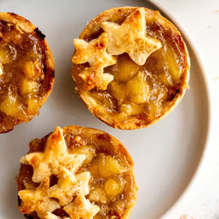 Mini apple pies on white plate.