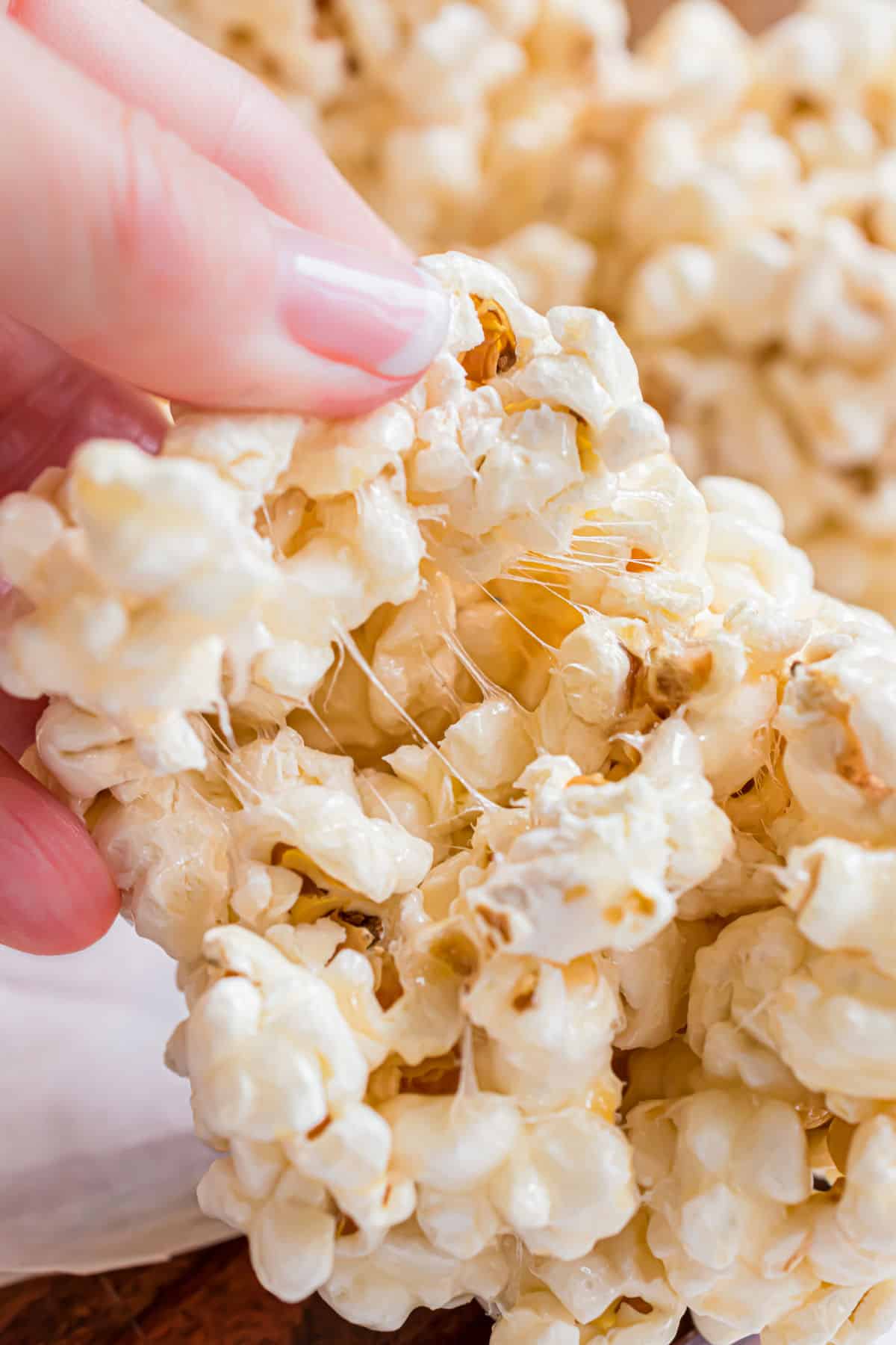 Popcorn ball being pulled in half to show chewy texture.