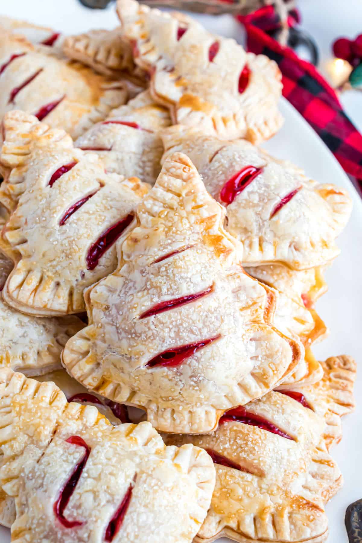 Cherry hand pies shaped like trees stacked on a white serving plate.