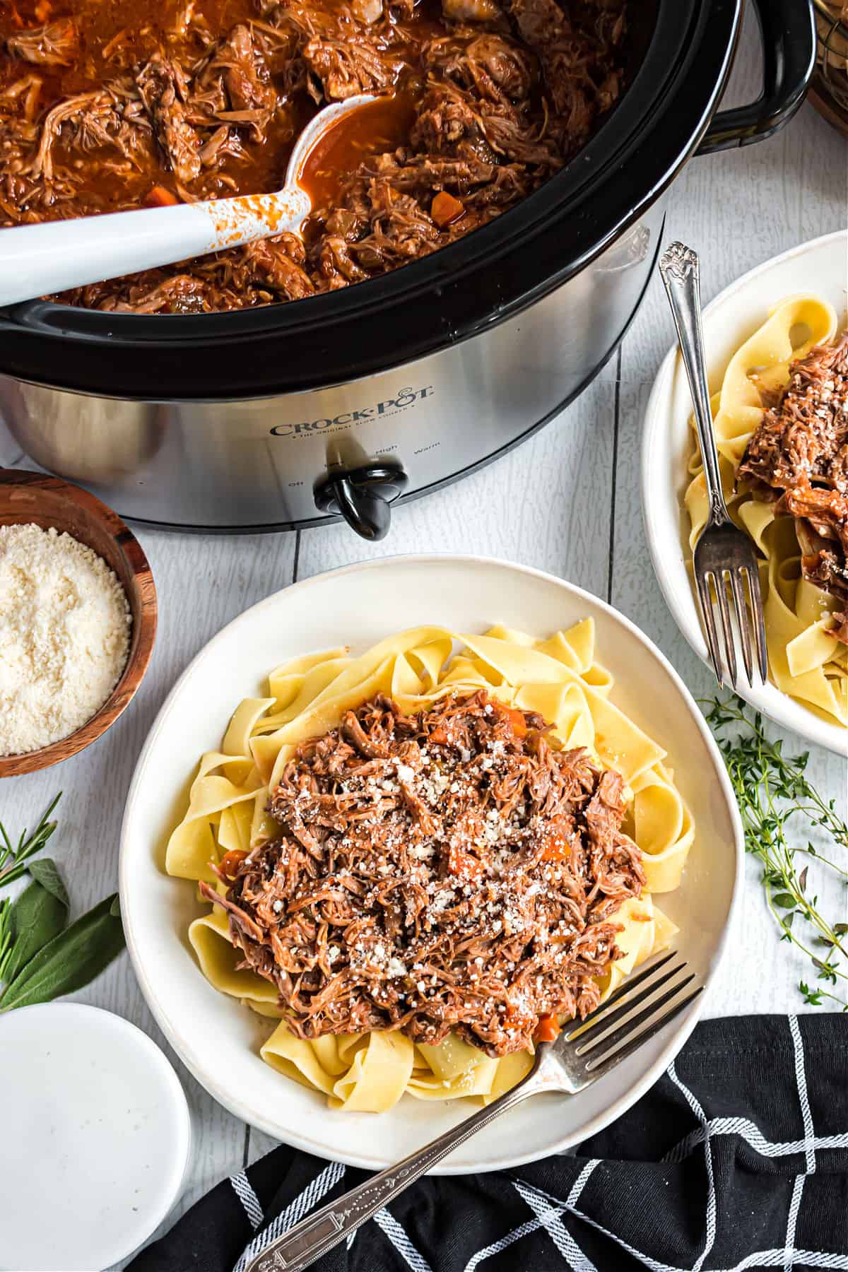 Pork ragu served over pappardelle pasta on a white plate.