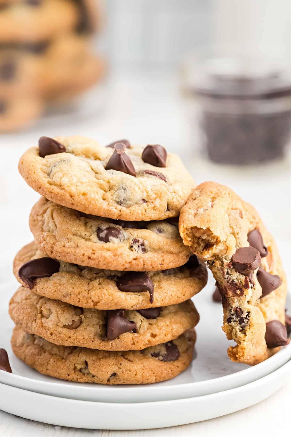 Stack of five toll house cookies on a white plate, with one leaning up against the stack.