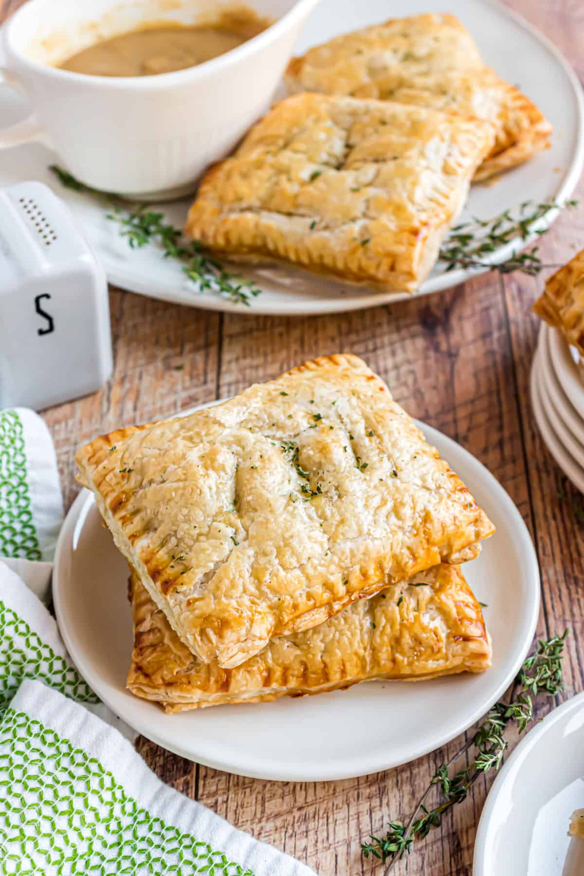 Turkey hand pies stacked on a white plate after baking.