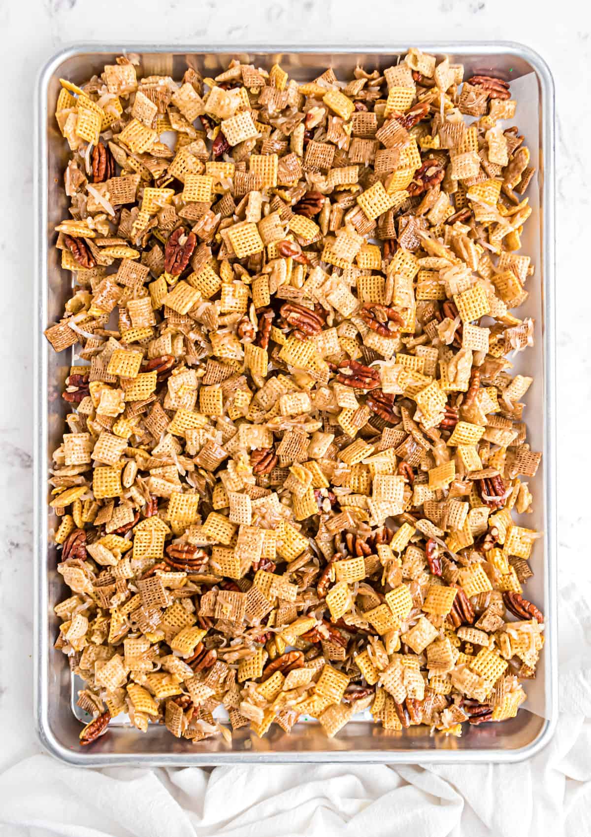 Sweet chex mix on a parchment paper lined cookie sheet.