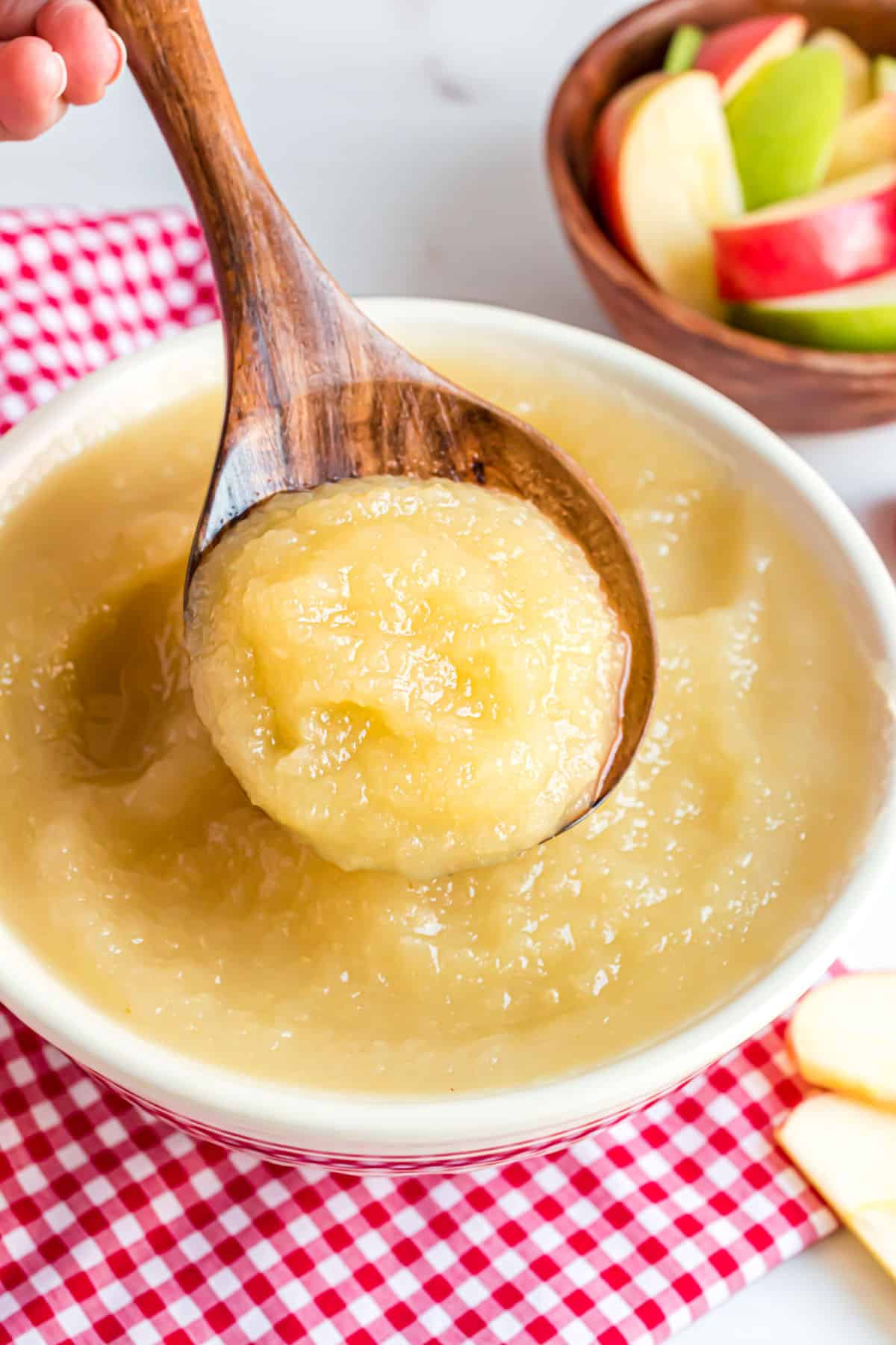 Applesauce in a white bowl served with a wooden spoon.