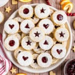 Large white serving platter with linzer cookies stacked on top.