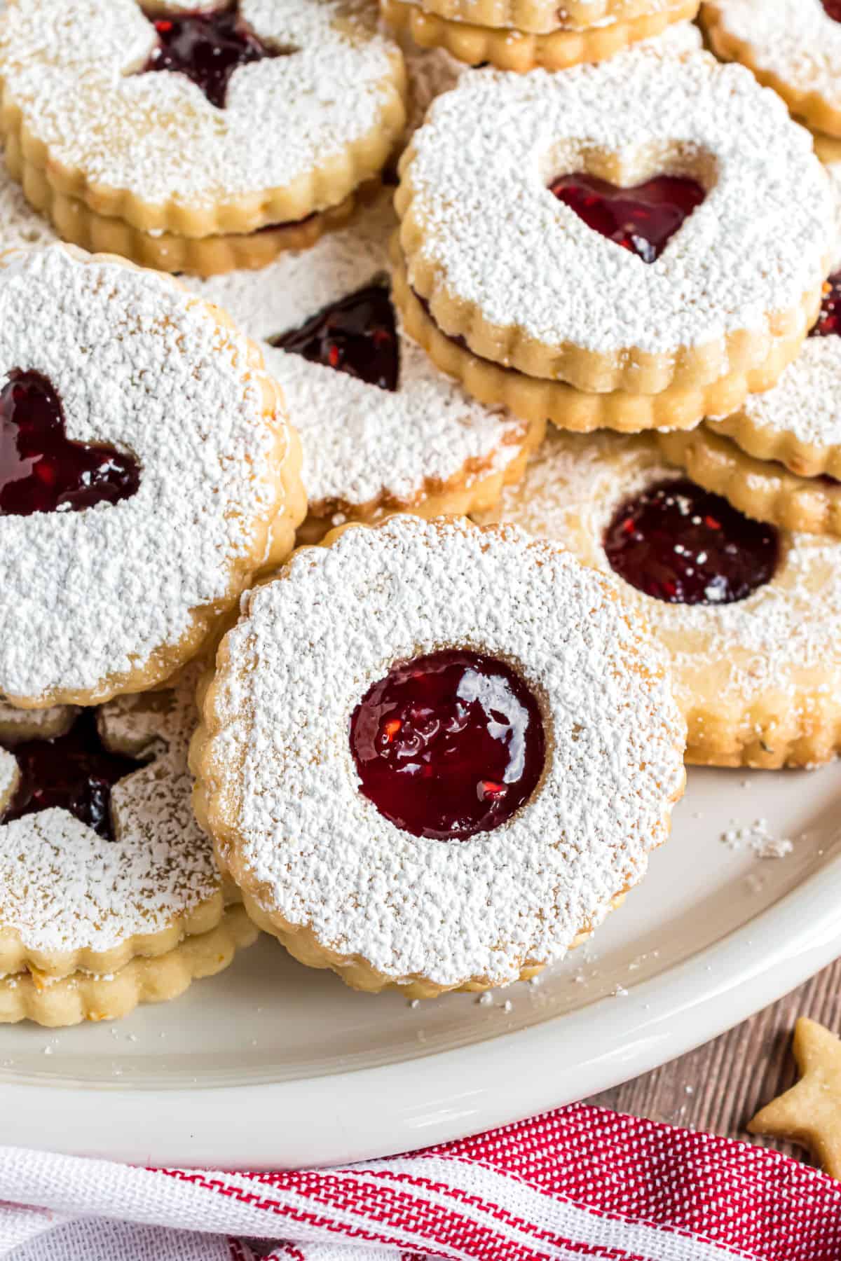 Linzer cookies stacked on a white serving plate.