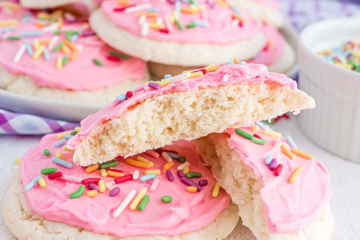 Stack of two homemade lofthouse cookies with pink frosting, one cookie cut in half.
