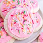 Stack of homemade lofthouse cookies with pink frosting on a white plate.