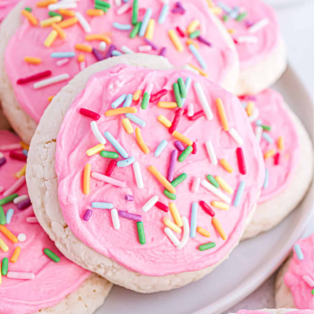 Stack of homemade lofthouse cookies with pink frosting on a white plate.