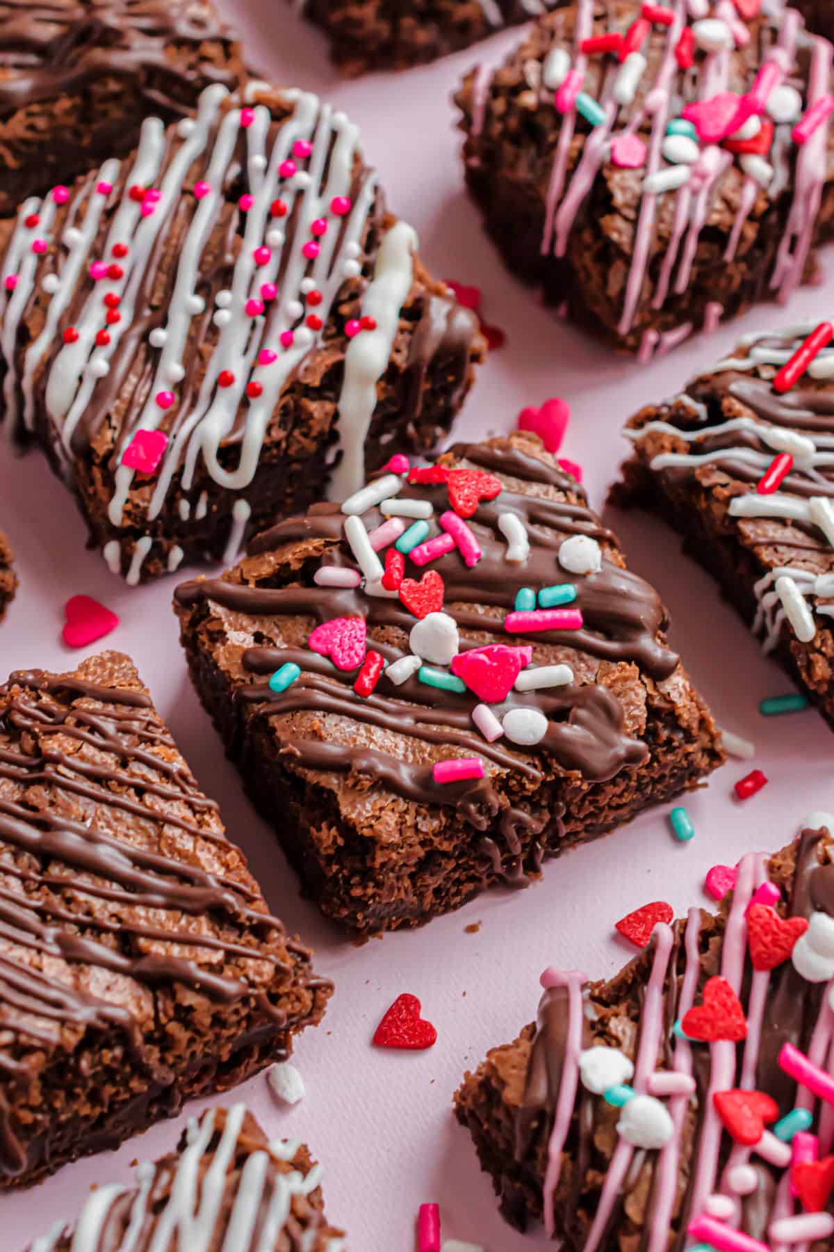 Brownie bites decorated with melted chocolate and valentine's day sprinkles.