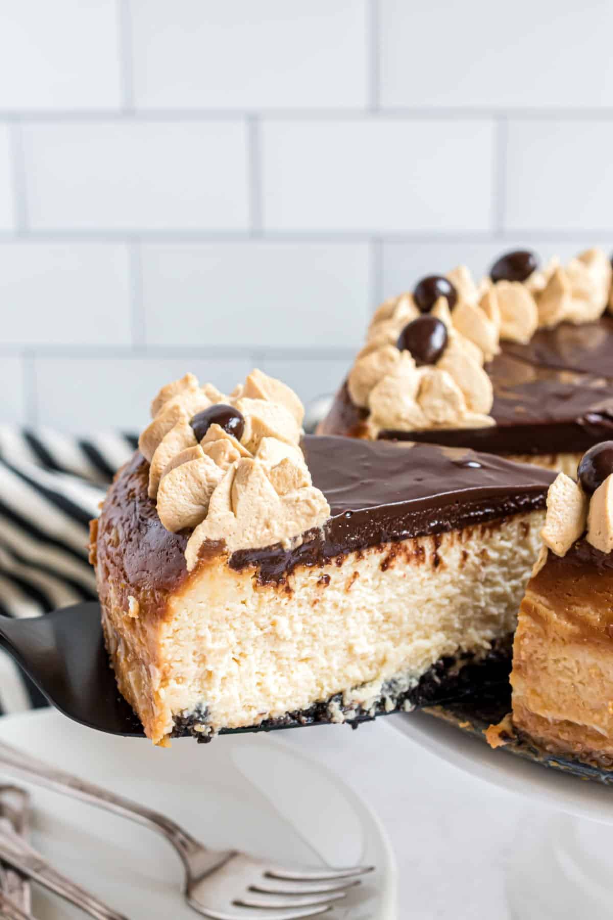 Slice of baileys cheesecake being lifted off cake platter.