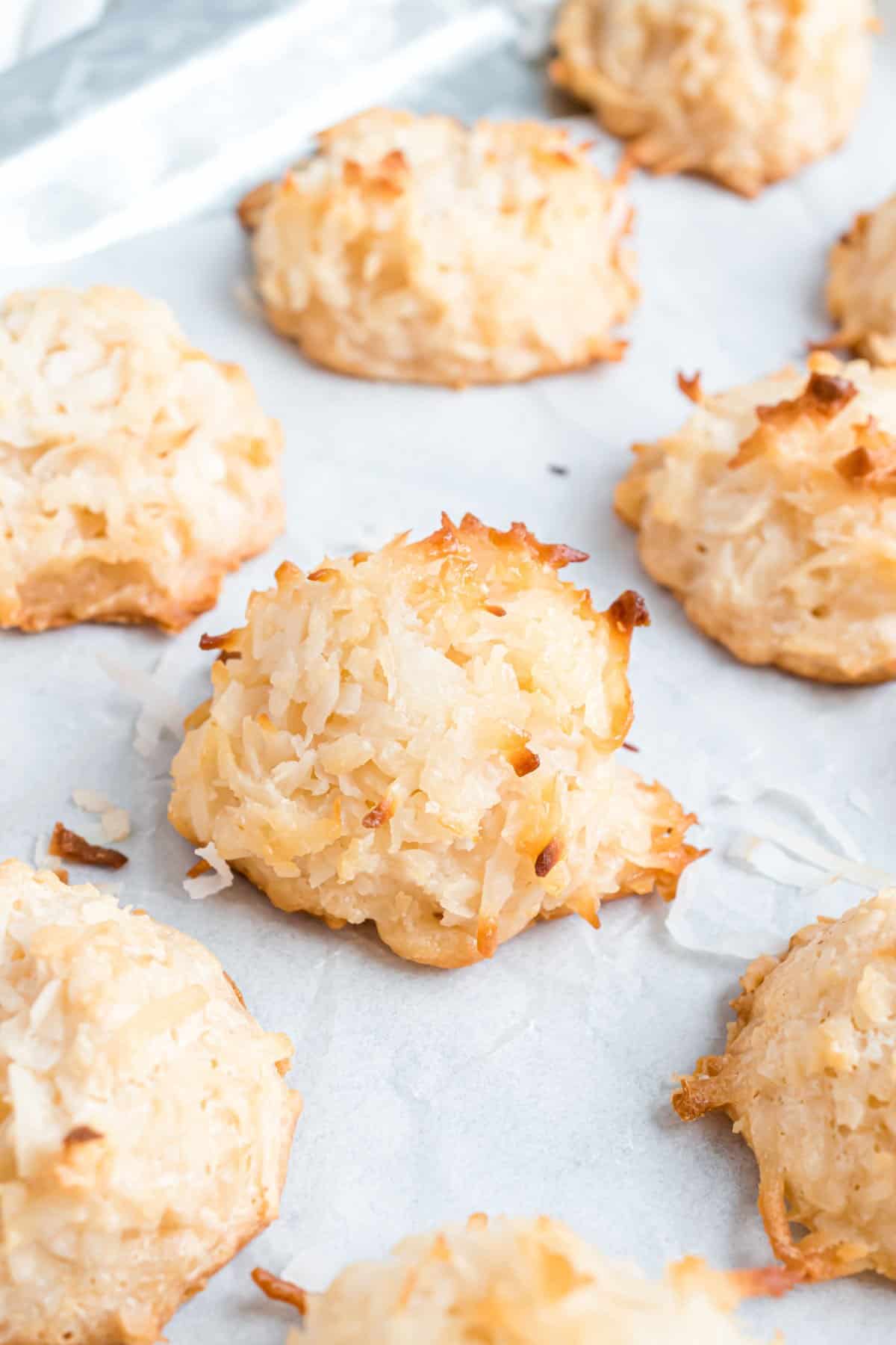 Coconut macaroons baked on a parchment paper lined cookie sheet.