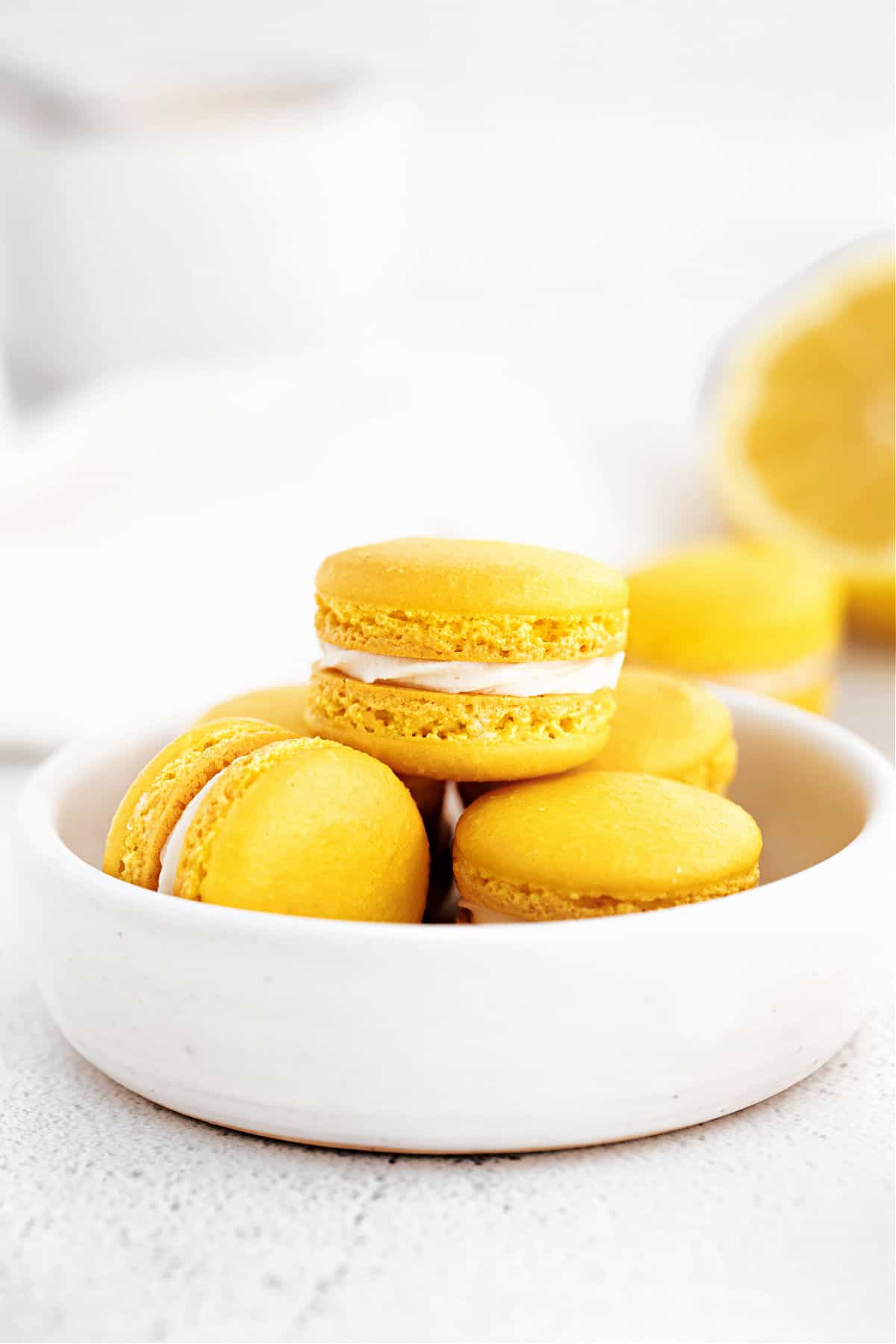 Lemon macarons stacked in a white bowl.