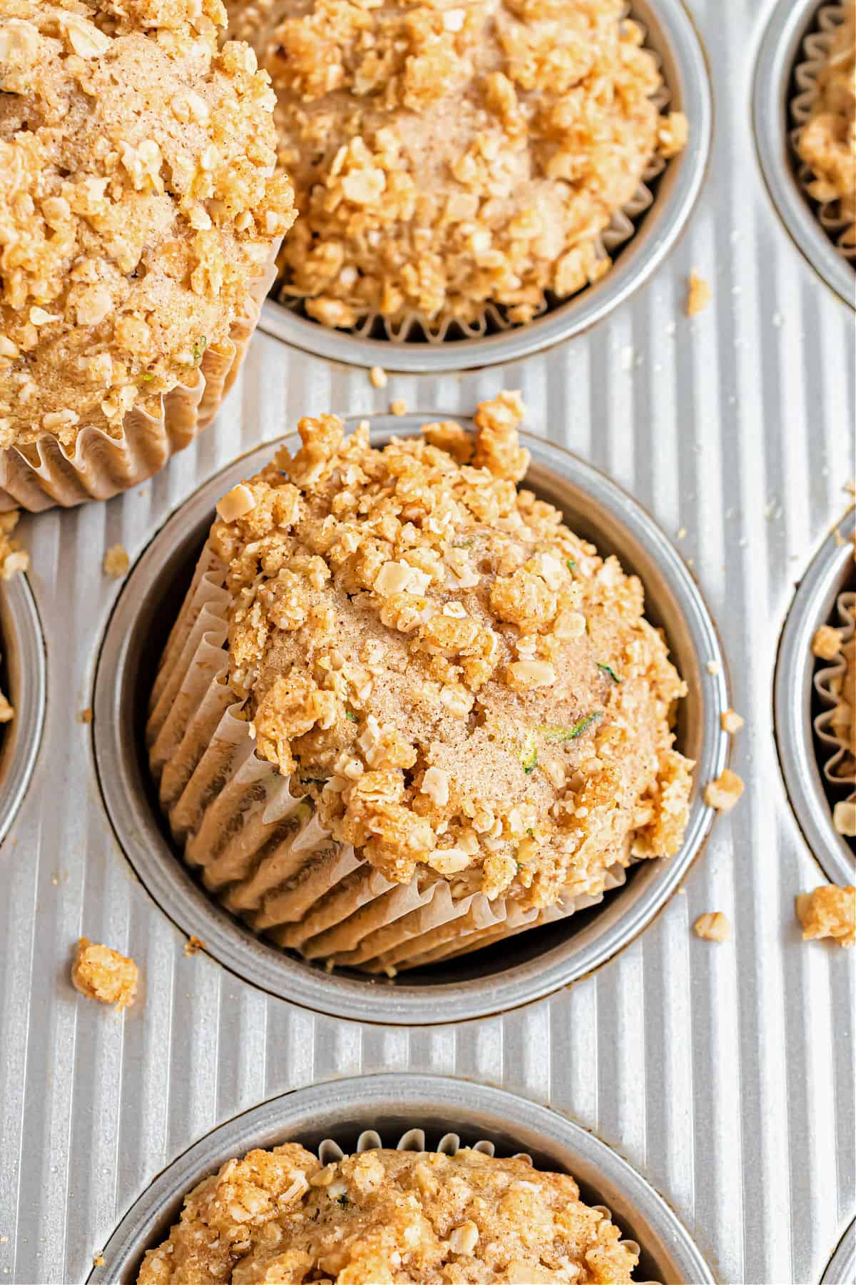 Muffins in a muffin tin with zucchini and streusel.