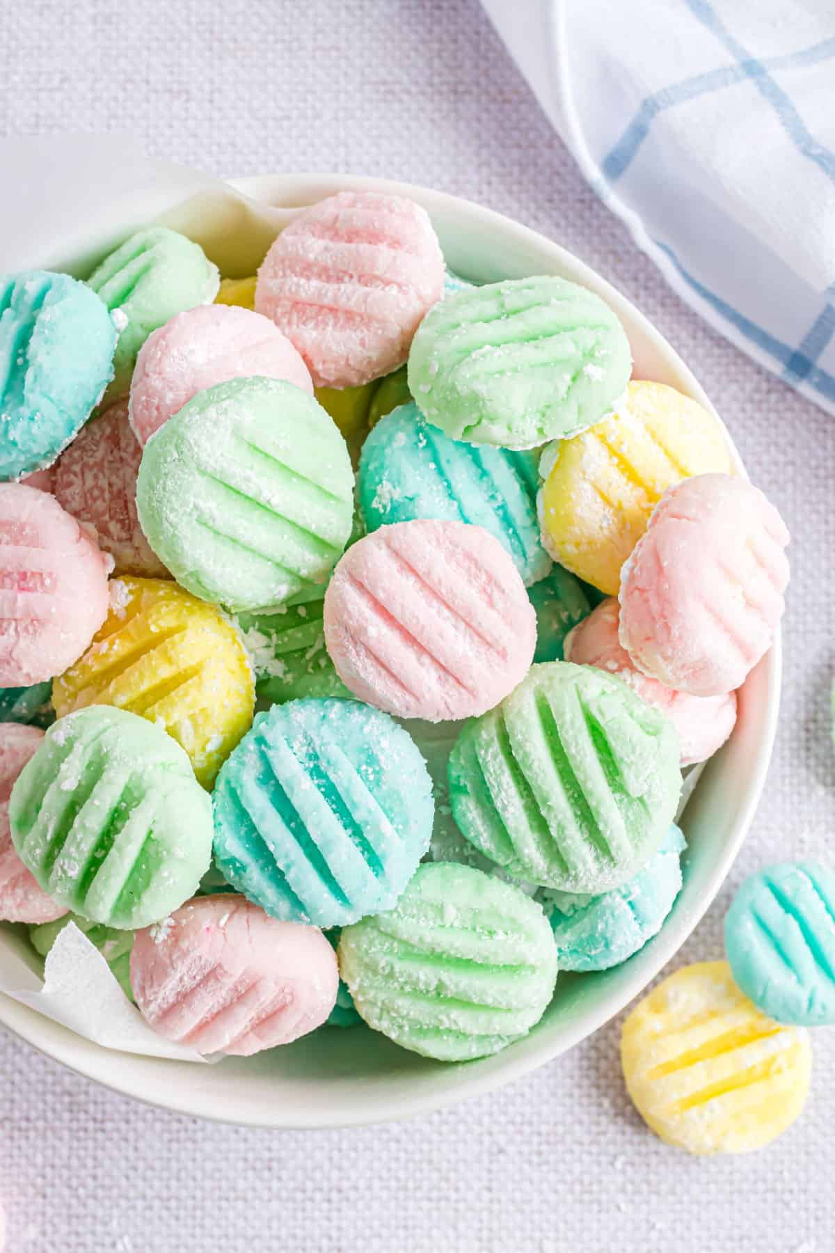 Cream cheese mints in a white bowl and colored with pastel colors.