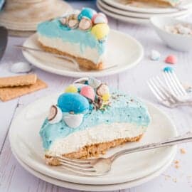 Turn heads with this vibrant Easter Egg Cheesecake at your holiday meal. A no-bake cheesecake is covered in whipped cream frosting and robin's egg malt balls. The spring time colors make the creamy homemade cheesecake even better!