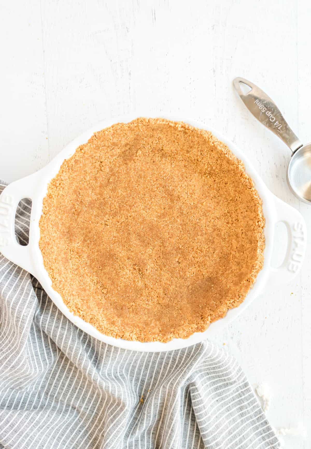 Graham cracker crust in a white pie plate.