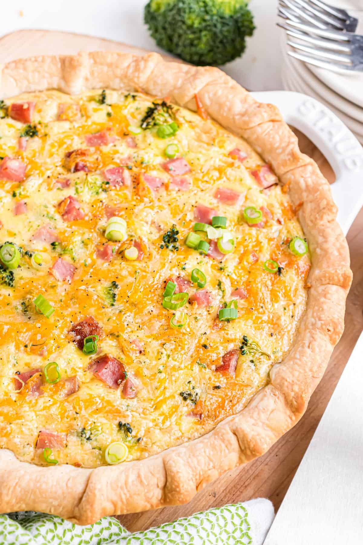 Baked ham and cheese quiche in a white pie plate.