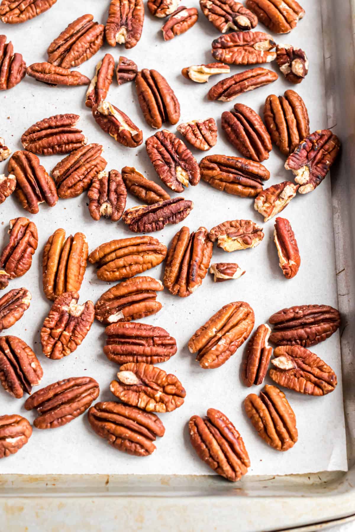 Pecans on a parchment paper lined cookie sheet for the oven.