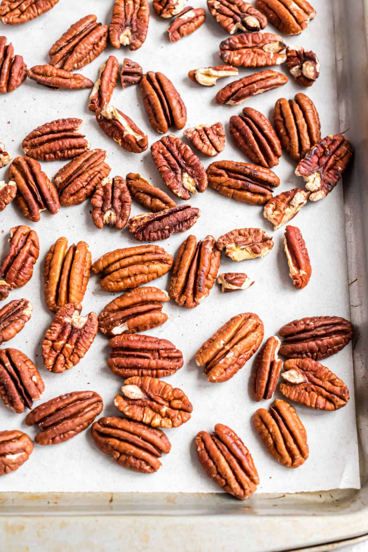 Pecans on a parchment paper lined cookie sheet for the oven.