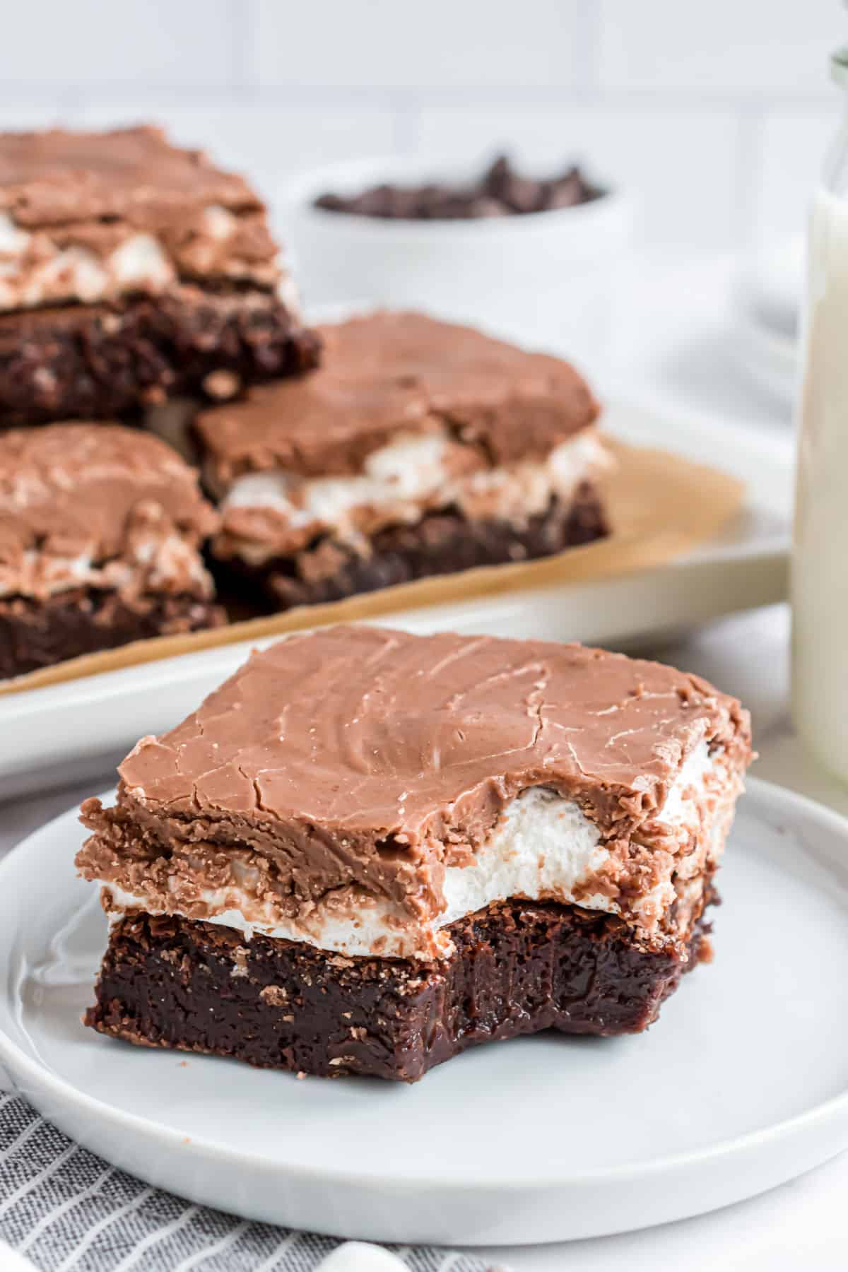 Brownies with a layer of marshmallow and chocolate icing with a bite taken out.
