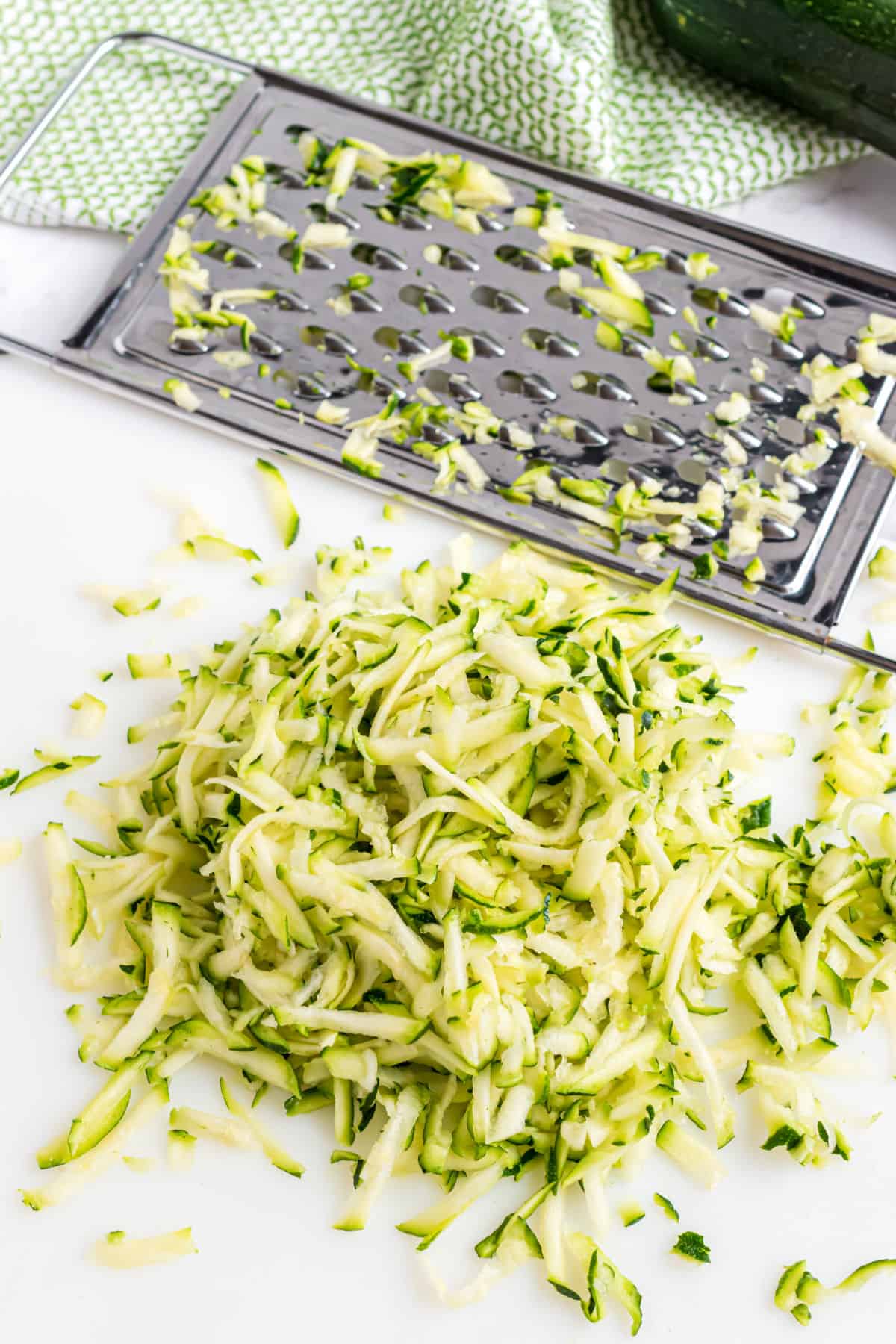 Shredded zucchini in a pile on a cutting board.