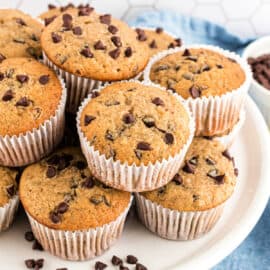 Stack of muffins on white cake plate with chocolate chips.