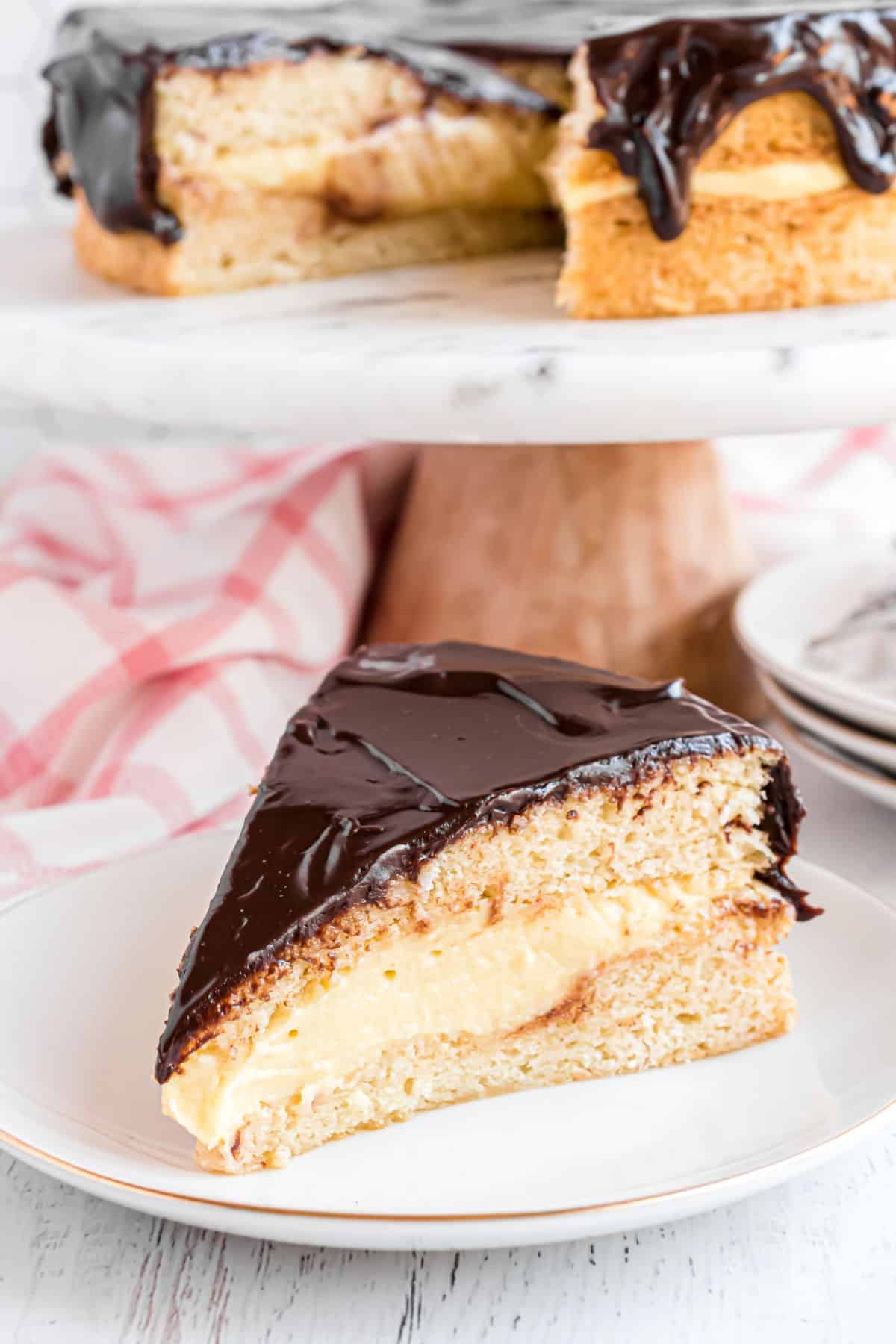 Slice of boston cream pie on a white plate.