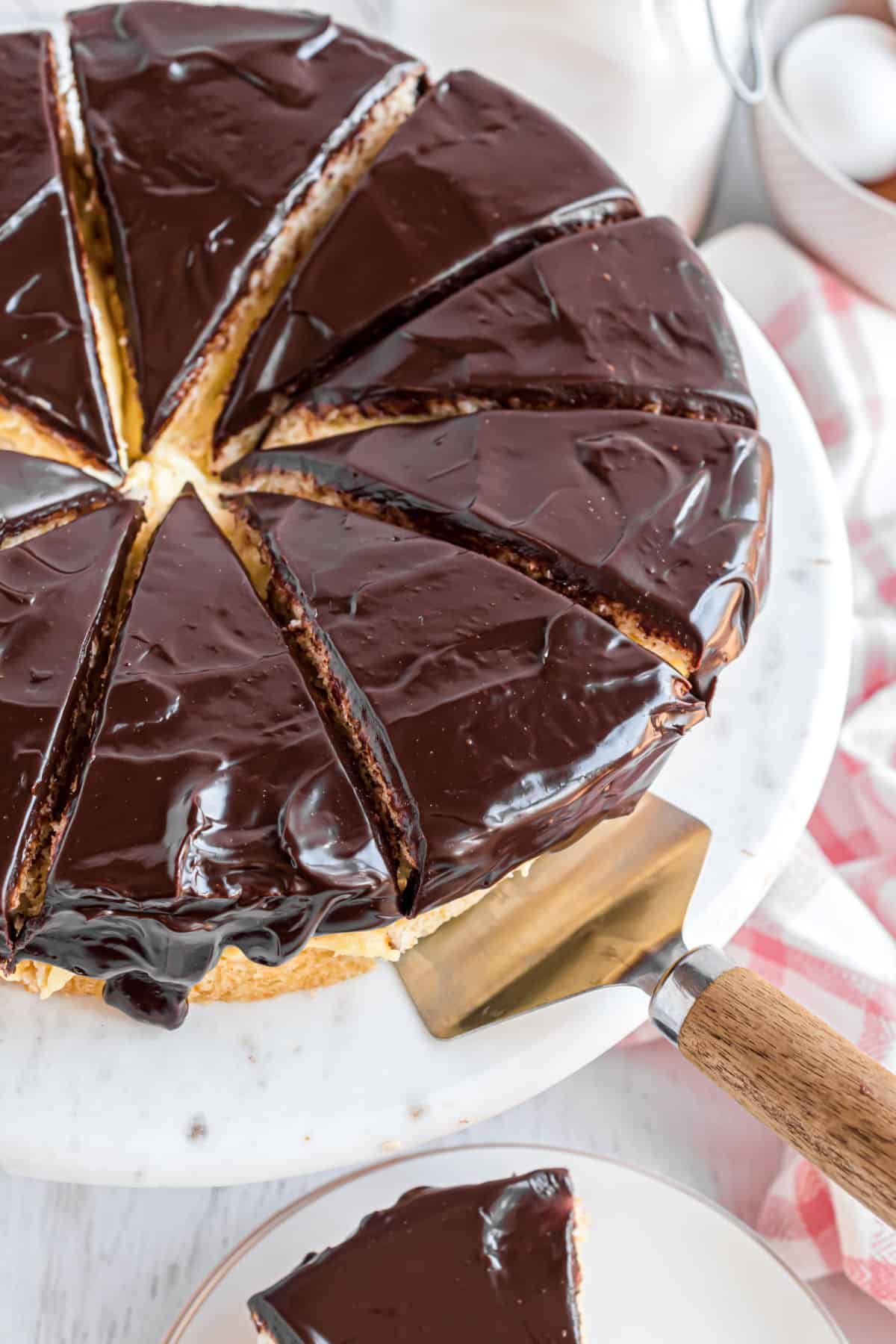 Boston cream pie cut into slices on a cake plate.