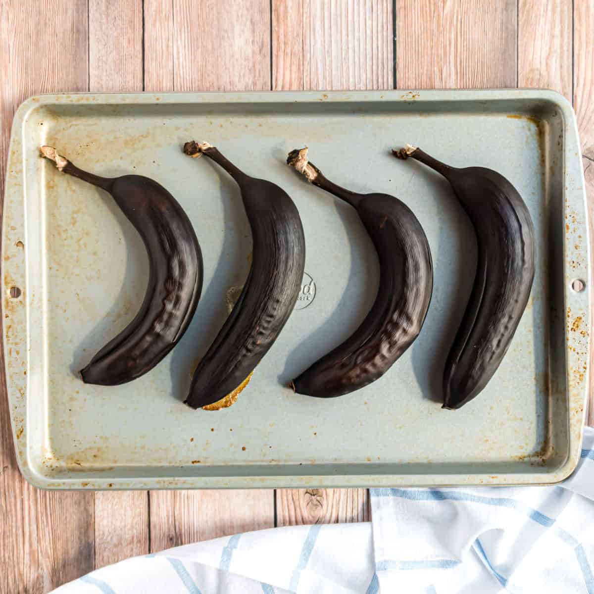 Black ripe bananas on a cookie sheet.