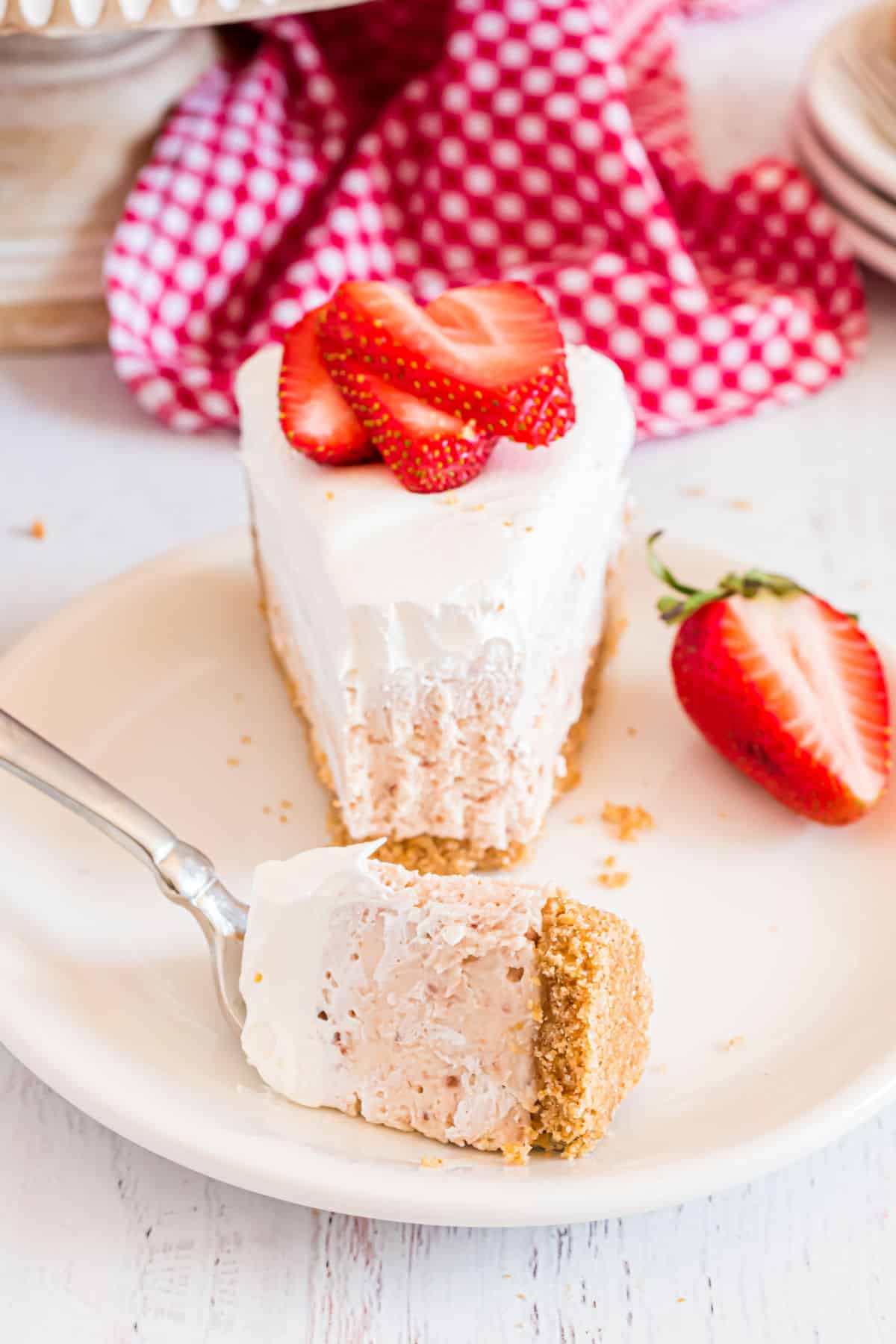 Slice of strawberry cheesecake with a bite taken.