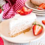 Slice of strawberry cheesecake on a white plate garnished with fresh strawberries.