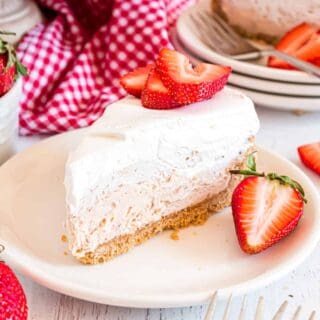 Slice of strawberry cheesecake on a white plate garnished with fresh strawberries.