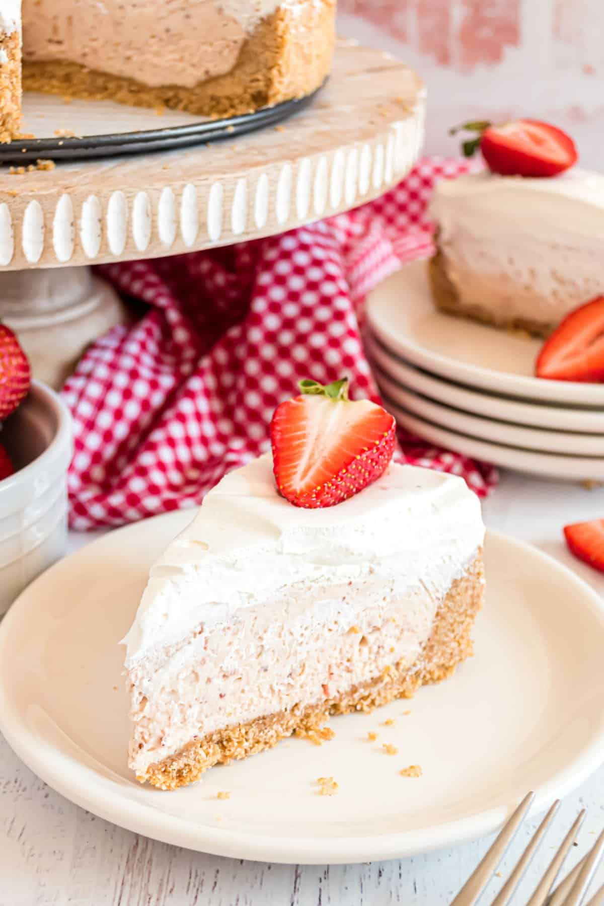 Slice of strawberry cheesecake with whipped creamand strawberry on top.