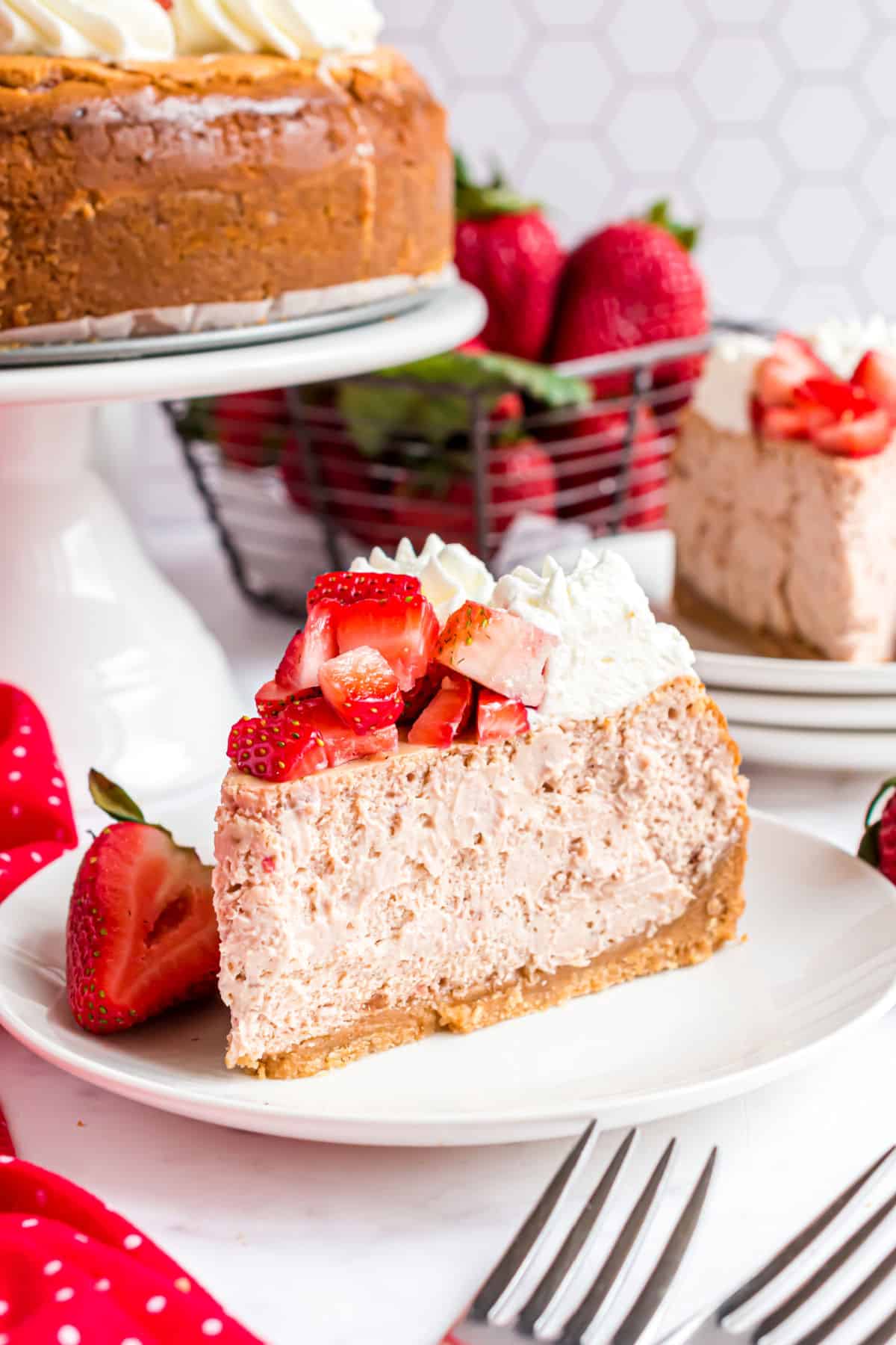 Slice of strawberry cheesecake on a white plate with fresh berries.