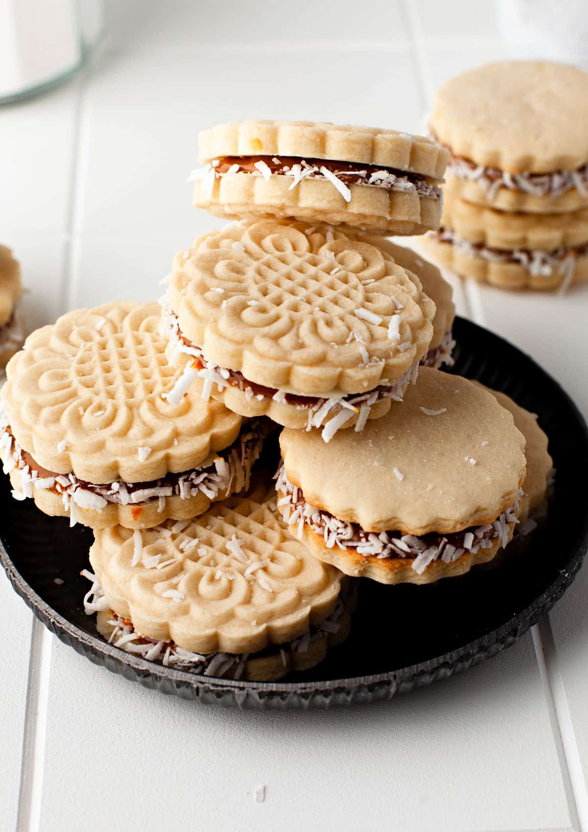 Stack of alfajores cookies on a black plate.