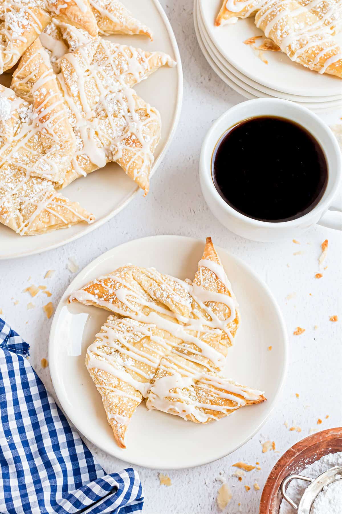 Cheese danish on a white plate with a mug of black coffee.