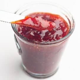 Strawberry jam in a clear glass jar.