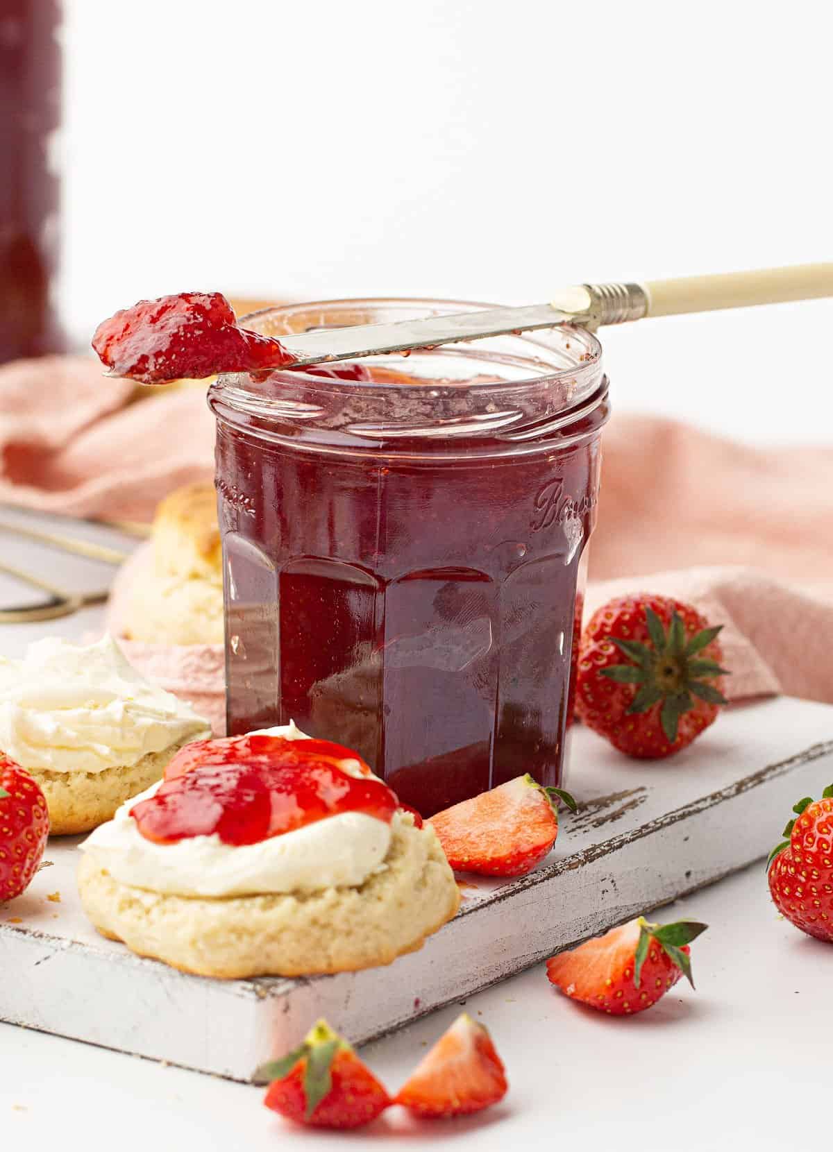 Strawberry jam with biscuits and fresh strawberries.