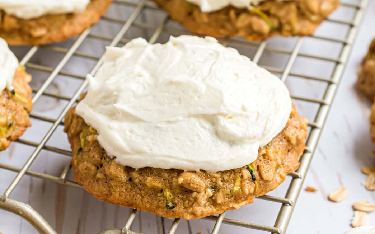 Zucchini cookie with frosting on a wire cooling rack.