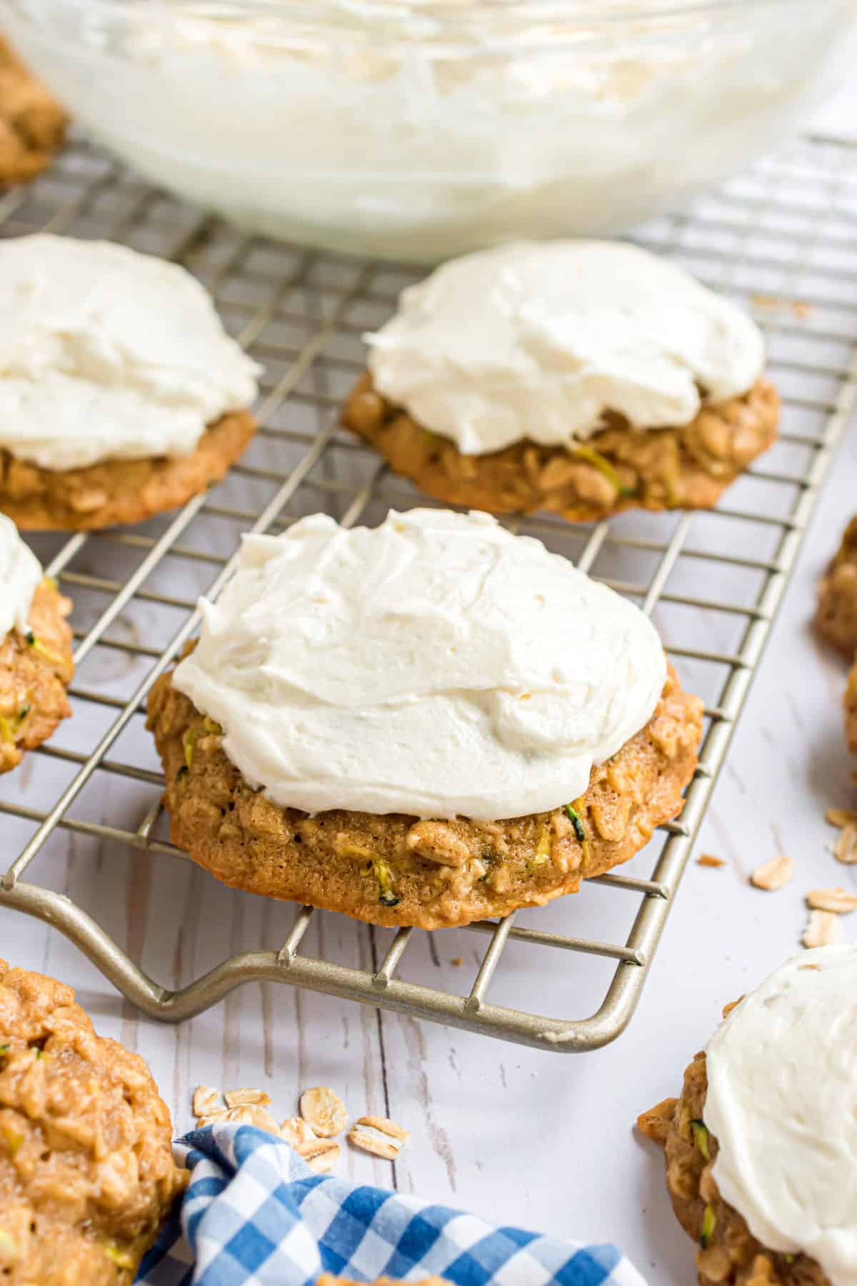 Zucchini cookies with cream cheese frosting on a wire cooling rack.