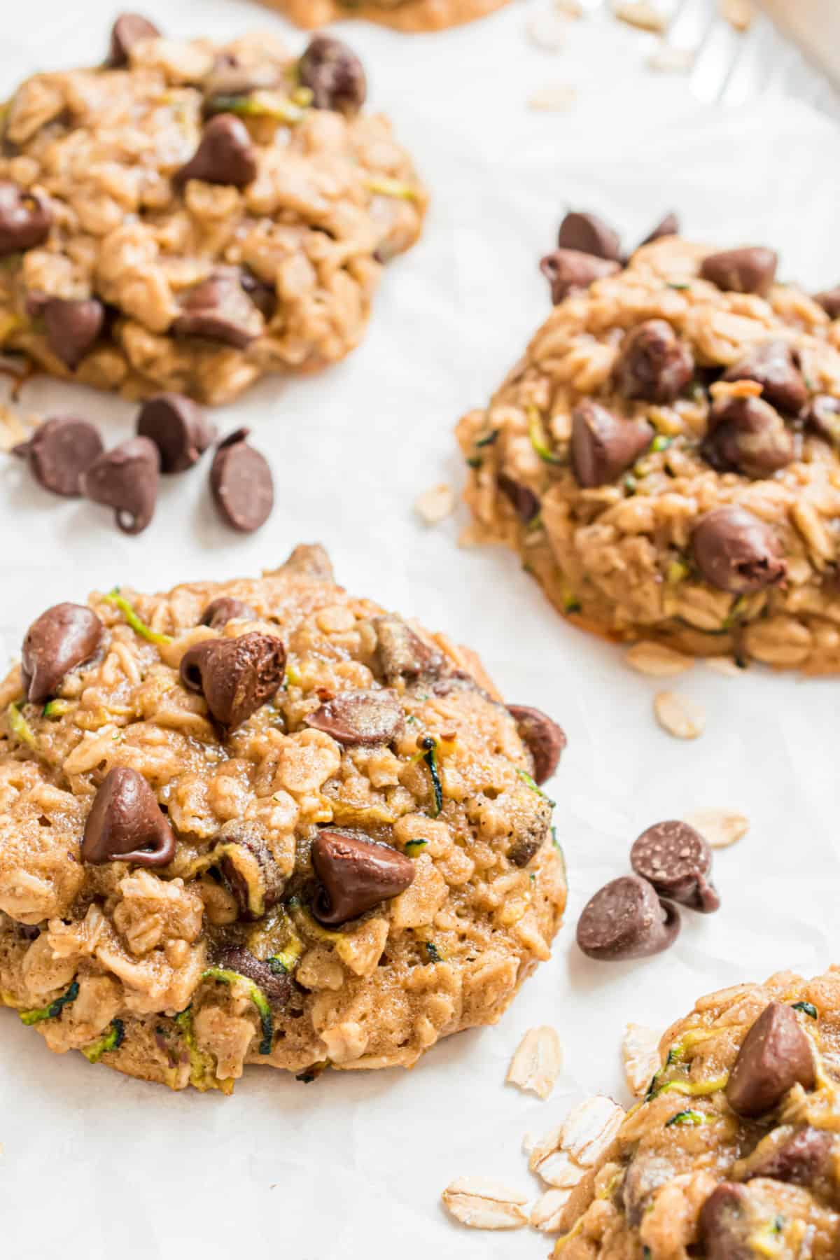 Chocolate chip oatmeal cookies baked on a parchment paper cookie sheet.