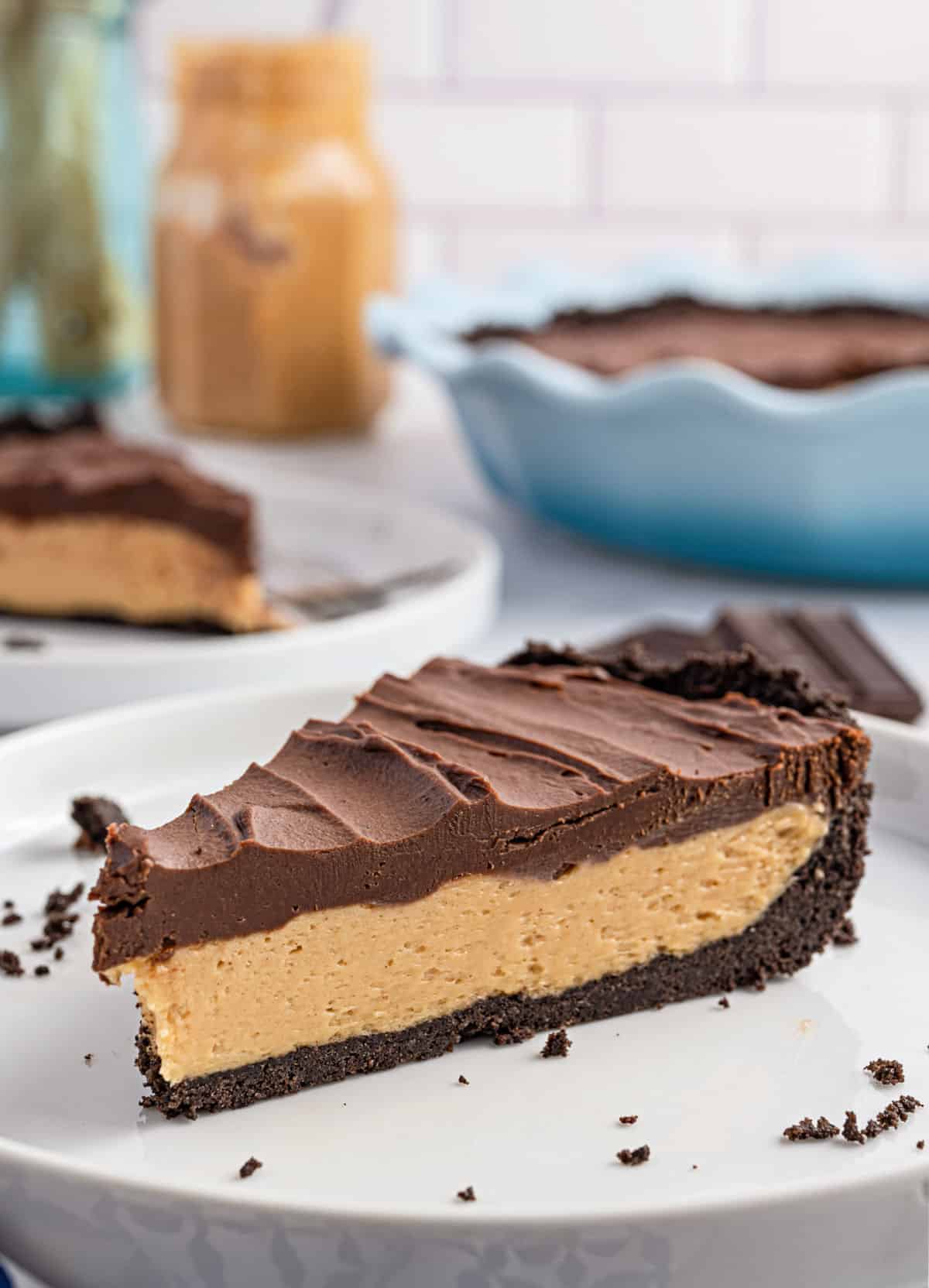 Slice of peanut butter pie with chocolate ganache on a white plate.