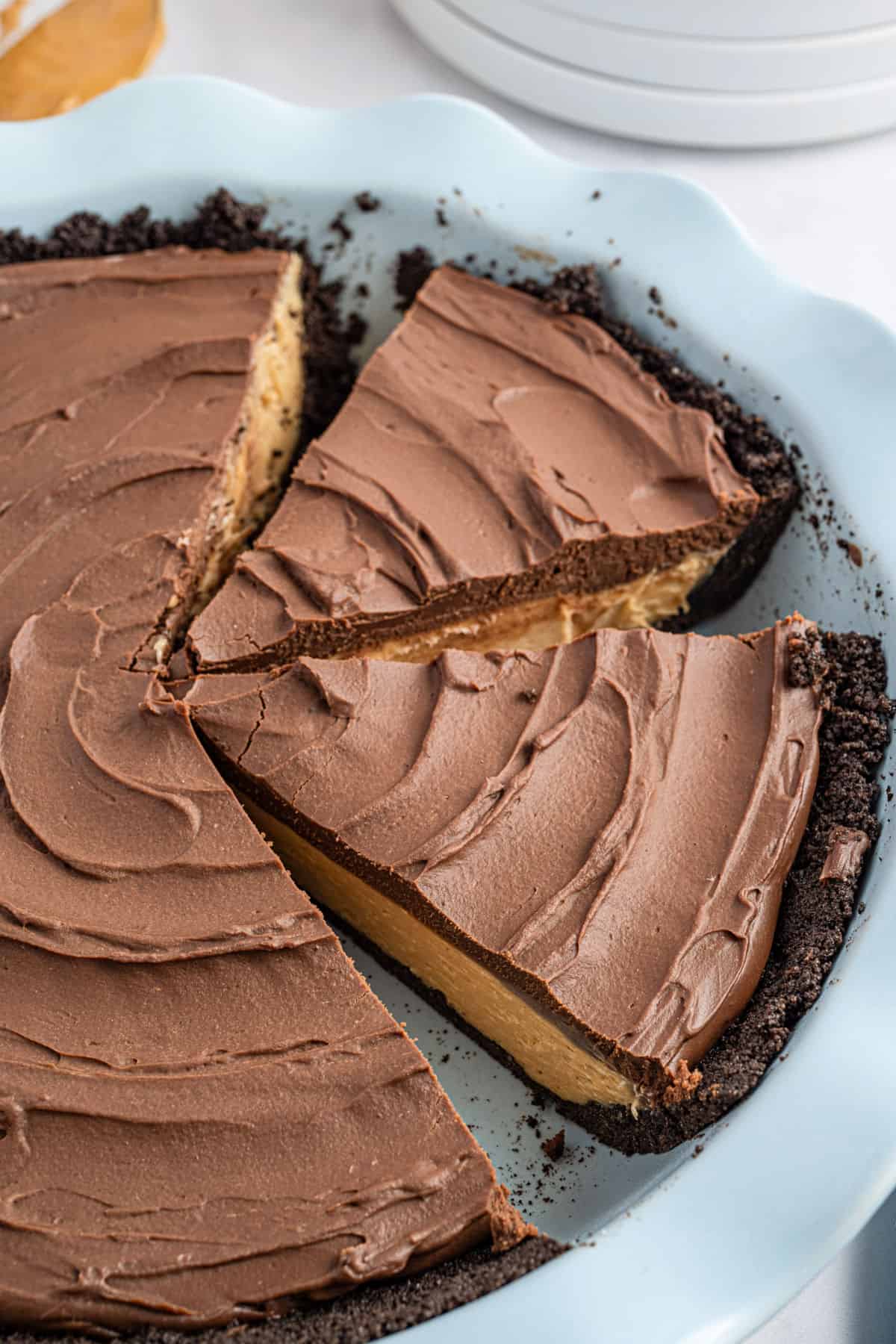 Peanut butter pie in a blue pie plate and topped with chocolate ganache.