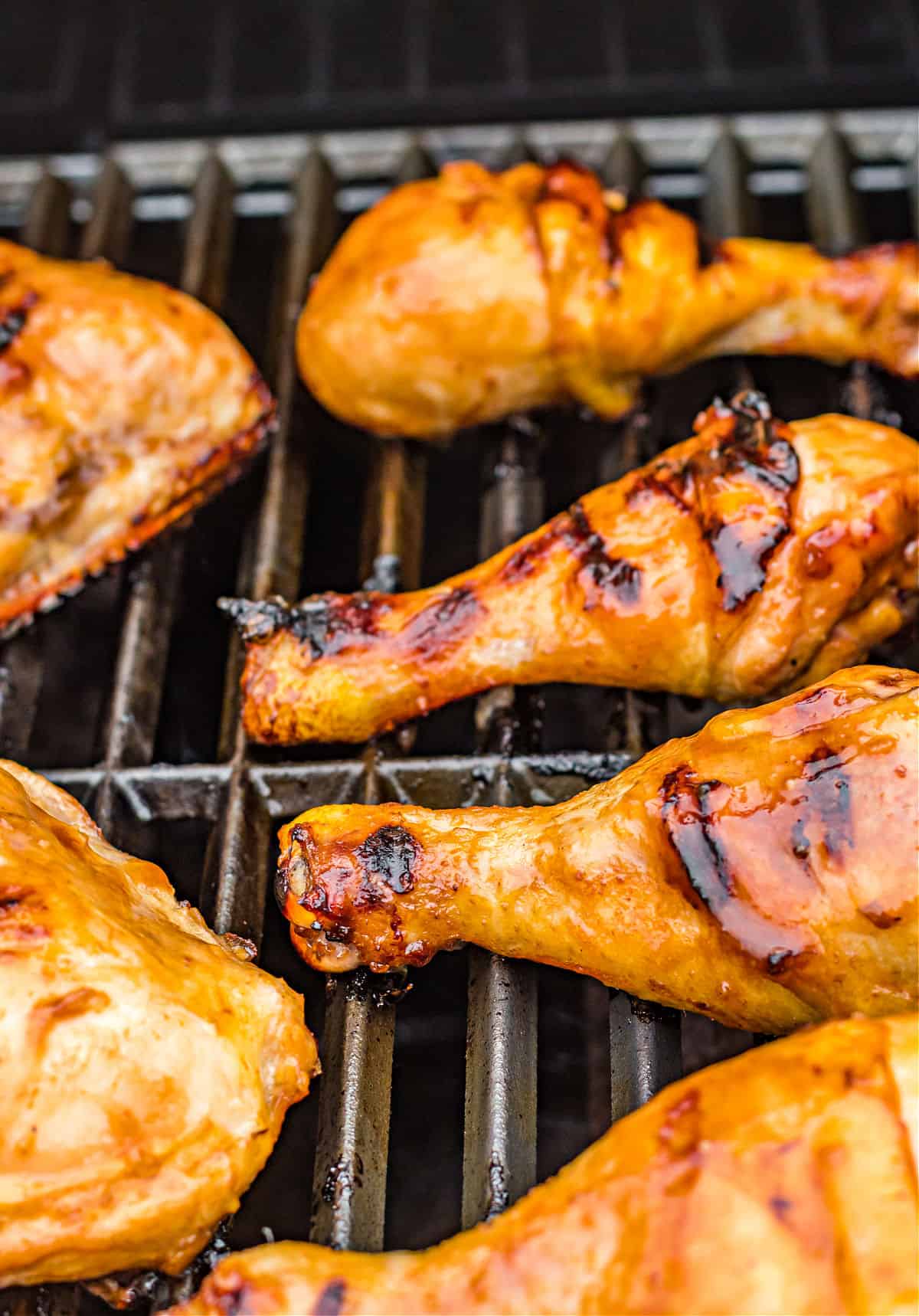 Grilled huli huli chicken legs on grill grates.