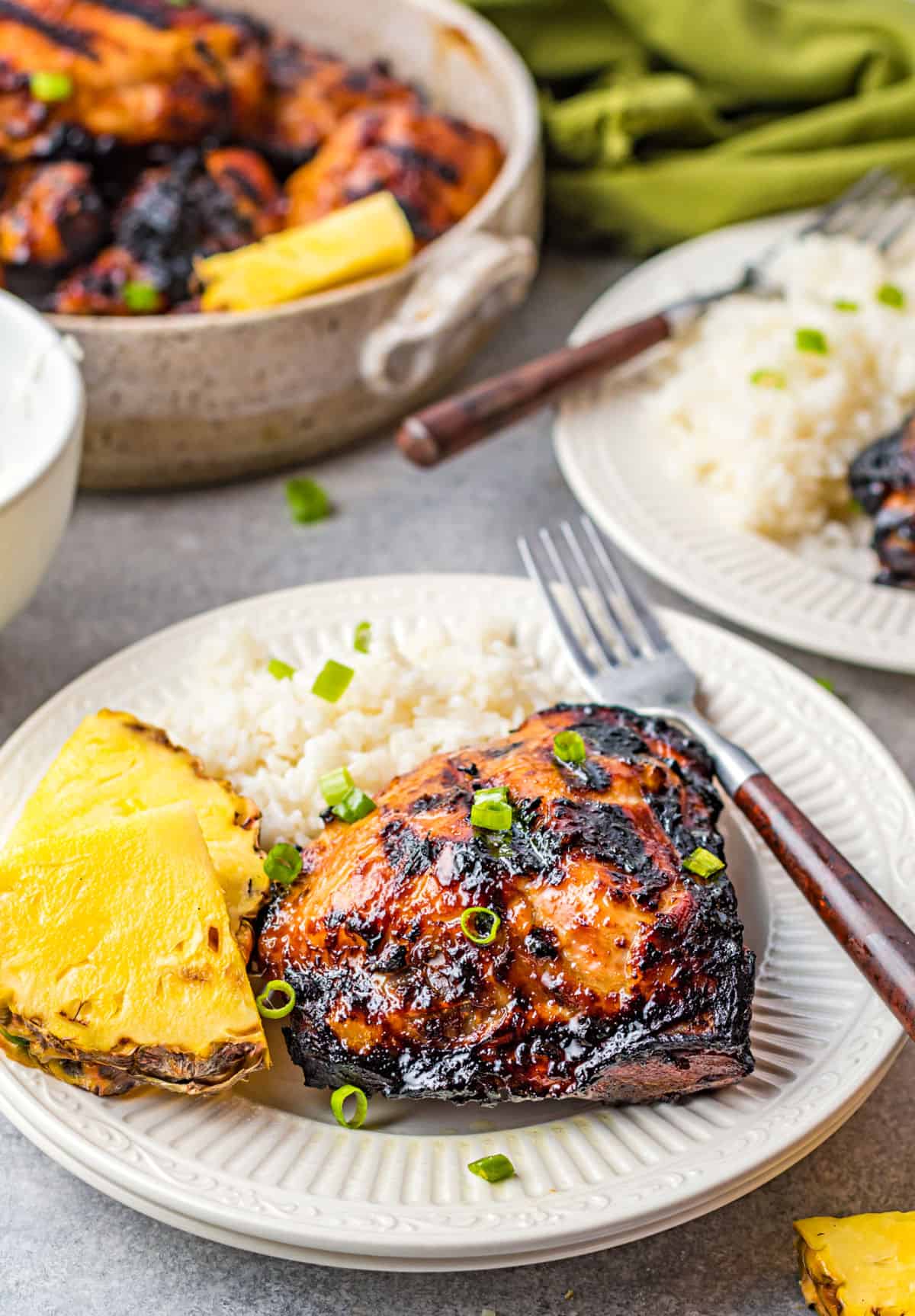 Huli huli grilled chicken on a plate with rice and pineapple.