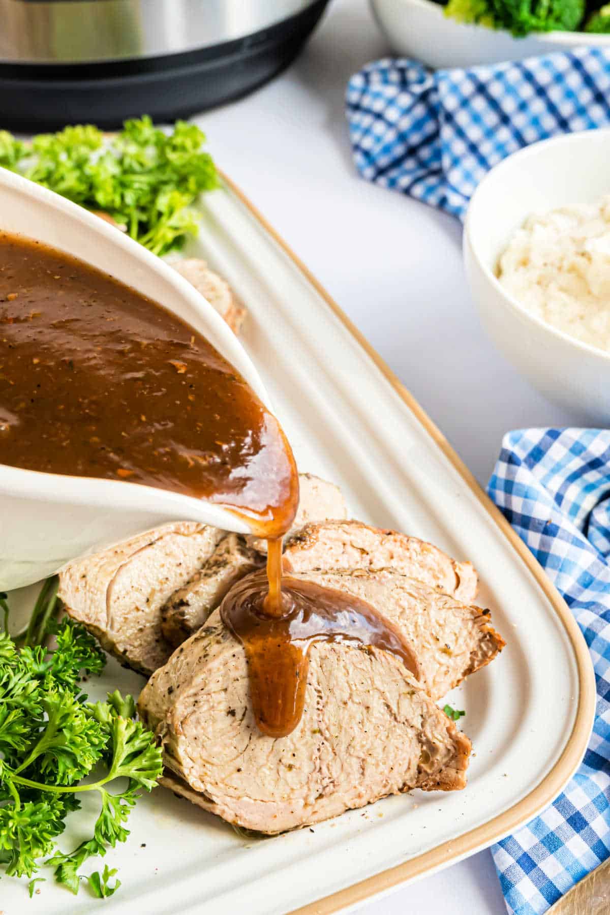 Slices of pork with gravy being drizzled over the top.