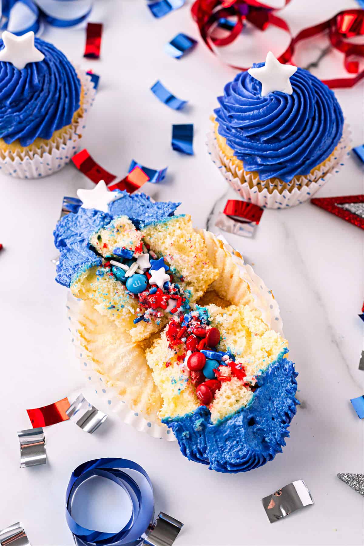 White cupcakes cut in half and filled with sprinkles.